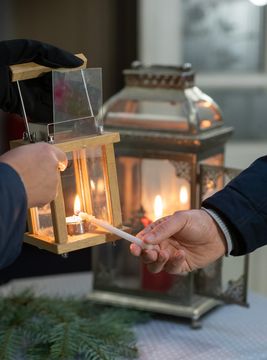 Mit einer langen Kerze wird das Friedenslicht von Laterne zu Laterne weitergegeben